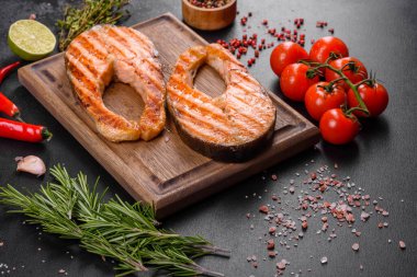 Taze pişirilmiş lezzetli somon bifteği, baharatlar ve ızgarada pişirilmiş otlar. Sağlıklı deniz ürünleri