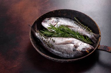 Raw dorado with spices and herbs in a pan is prepared for baking. Seafood preparation