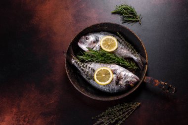 Raw dorado with spices and herbs in a pan is prepared for baking. Seafood preparation