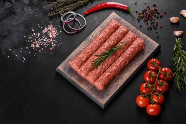 Koyu beton arka planda baharat ve otlarla ızgara kebap için taze çiğ kıyma.