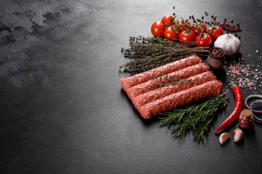 Koyu beton arka planda baharat ve otlarla ızgara kebap için taze çiğ kıyma.