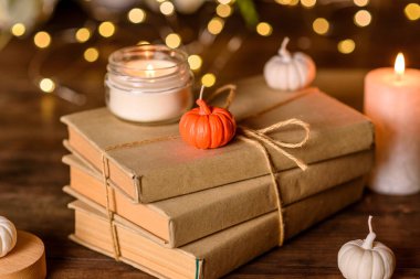 A burning candle on a wooden table in front of a book in a half-mast. Learning. Studying the Bible