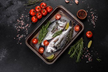 Kesme tahtasında baharatlı çiğ dorado balığı. Taze balık dorado. Dorado ve masada yemek yapmak için malzemeler.