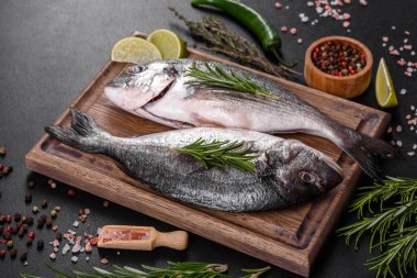 Kesme tahtasında baharatlı çiğ dorado balığı. Taze balık dorado. Dorado ve masada yemek yapmak için malzemeler.