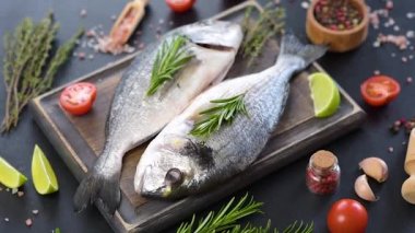 Kesme tahtasında baharatlı çiğ dorado balığı. Taze balık dorado. Dorado ve masada yemek yapmak için malzemeler.