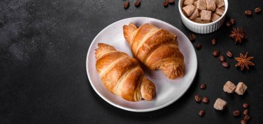 Taze taze Fransız kruvasanı ve koyu beton arka planda bir fincan mis kokulu kahve. Canlandırıcı kahvaltı.