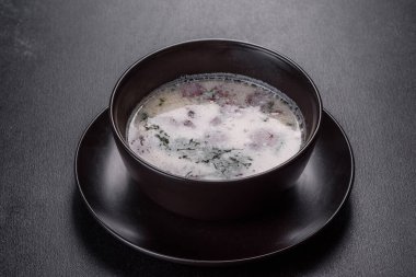 Kızarmış sosisli ve otlu peynir çorbası. Siyah tabakta lezzetli krem peynir çorbası. Yemek masası.