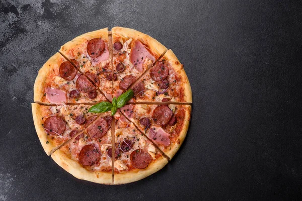 stock image Delicious fresh oven pizza with tomatoes, salami and bacon on a dark concrete background. Italian cuisine