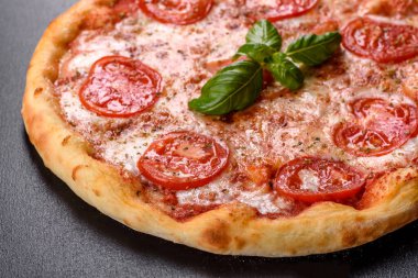 Lezzetli fırında pizza, domatesli ve peynirli koyu beton arka planda.