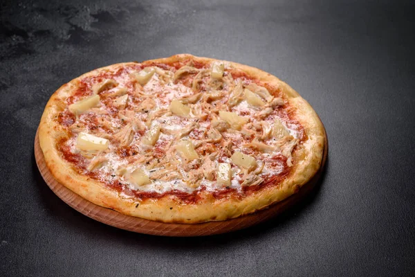 Homemade pizza Hawaiian with ham and pineapple on a dark background
