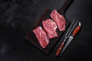 Çiğ ördek göğsü, otlar ve baharatlarla koyu beton bir arka planda. Pişirmeye hazır çiğ et.