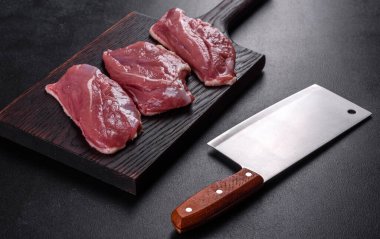 Çiğ ördek göğsü, otlar ve baharatlarla koyu beton bir arka planda. Pişirmeye hazır çiğ et.