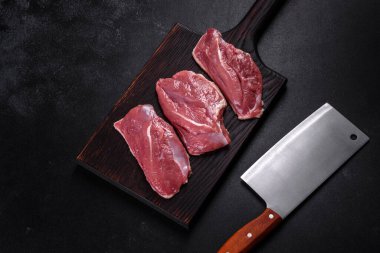 Çiğ ördek göğsü, otlar ve baharatlarla koyu beton bir arka planda. Pişirmeye hazır çiğ et.