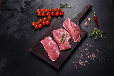 Çiğ ördek göğsü, otlar ve baharatlarla koyu beton bir arka planda. Pişirmeye hazır çiğ et.