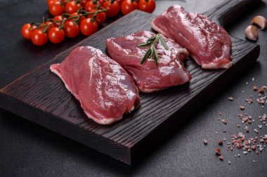 Çiğ ördek göğsü, otlar ve baharatlarla koyu beton bir arka planda. Pişirmeye hazır çiğ et.