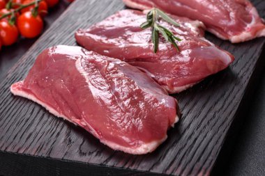 Çiğ ördek göğsü, otlar ve baharatlarla koyu beton bir arka planda. Pişirmeye hazır çiğ et.