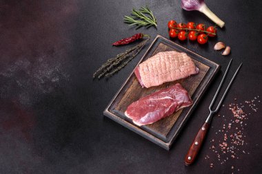 Çiğ ördek göğsü, otlar ve baharatlarla koyu beton bir arka planda. Pişirmeye hazır çiğ et.