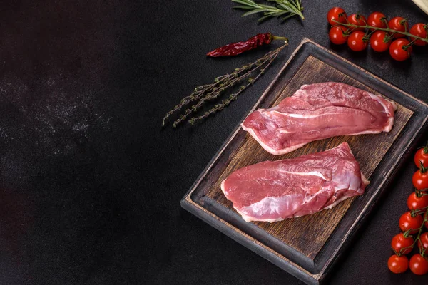 Raw duck breast with herbs and spices on a dark concrete background. Raw meat prepared for baking