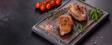 Koyu beton arka planda otlar ve baharatlarla pişirilmiş ördek göğsü. Kızarmış et yemek için hazır.