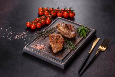 Koyu beton arka planda otlar ve baharatlarla pişirilmiş ördek göğsü. Kızarmış et yemek için hazır.