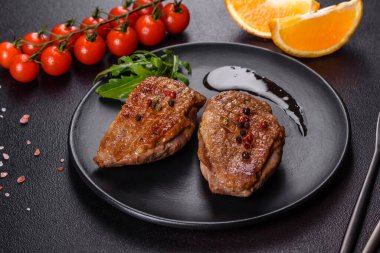 Koyu beton arka planda otlar ve baharatlarla pişirilmiş ördek göğsü. Kızarmış et yemek için hazır.