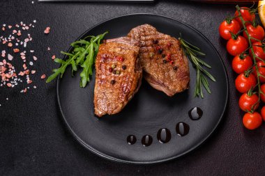 Koyu beton arka planda otlar ve baharatlarla pişirilmiş ördek göğsü. Kızarmış et yemek için hazır.