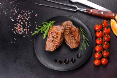 Koyu beton arka planda otlar ve baharatlarla pişirilmiş ördek göğsü. Kızarmış et yemek için hazır.