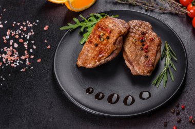 Koyu beton arka planda otlar ve baharatlarla pişirilmiş ördek göğsü. Kızarmış et yemek için hazır.