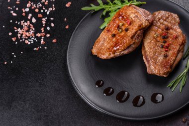 Koyu beton arka planda otlar ve baharatlarla pişirilmiş ördek göğsü. Kızarmış et yemek için hazır.