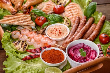 Izgarada hazırlanmış sosis, tavuk, domuz ve karidesin yanı sıra baharat ve otlarla ızgarada hazırlanmış sebzeler. Alevler içinde yemek yapmak