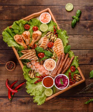 Izgarada hazırlanmış sosis, tavuk, domuz ve karidesin yanı sıra baharat ve otlarla ızgarada hazırlanmış sebzeler. Alevler içinde yemek yapmak