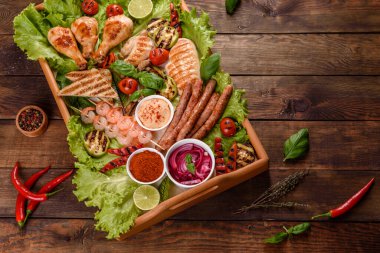 Izgarada hazırlanmış sosis, tavuk, domuz ve karidesin yanı sıra baharat ve otlarla ızgarada hazırlanmış sebzeler. Alevler içinde yemek yapmak