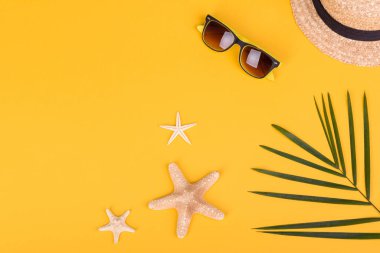 Plaj aksesuarları: kabuklu gözlük ve şapka ve renkli arka planda deniz yıldızları. Yaz arkaplanı