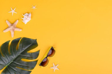 Plaj aksesuarları: kabuklu gözlük ve şapka ve renkli arka planda deniz yıldızları. Yaz arkaplanı