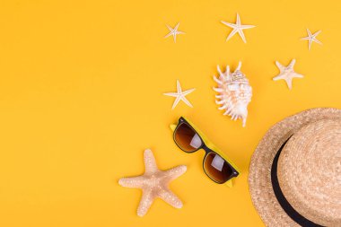 Plaj aksesuarları: kabuklu gözlük ve şapka ve renkli arka planda deniz yıldızları. Yaz arkaplanı
