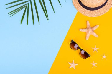 Plaj aksesuarları: kabuklu gözlük ve şapka ve renkli arka planda deniz yıldızları. Yaz arkaplanı