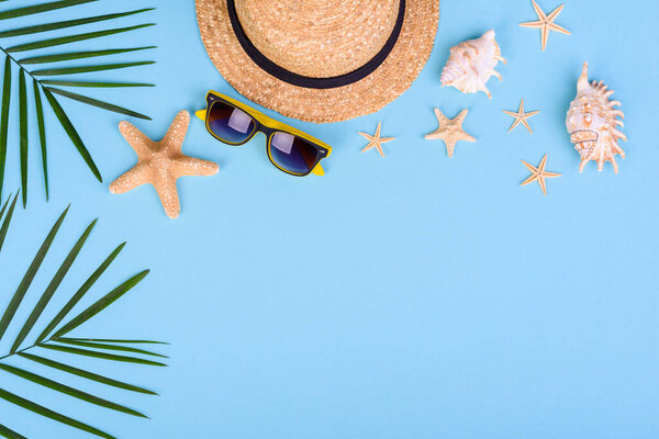 Beach accessories: glasses and hat with shells and sea stars on a colored background. Summer background