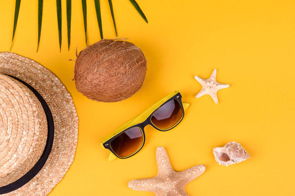 Beach accessories: glasses and hat with shells and sea stars on a colored background. Summer background