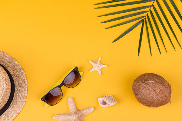 Beach accessories: glasses and hat with shells and sea stars on a colored background. Summer background