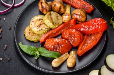 Lezzetli taze sebze ızgarası: domates, biber, mantar, kabak ve siyah tabakta soğan. Lezzetli sağlıklı yemek.