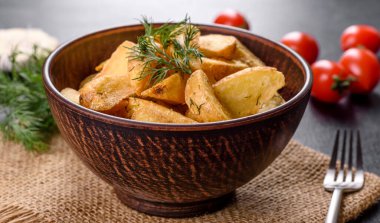 Kahverengi bir tabakta baharat ve otlarla, kırsal bir şekilde pişirilmiş lezzetli patatesler. Sağlıksız yiyecekler