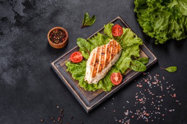 Koyu beton arka planda tavuk, domates ve marul parçaları. Lezzetli sağlıklı yemek.