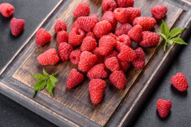 Karanlık bir masada nefis taze kırmızı ahududular. Mevsimlik meyve ve meyveler