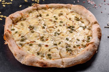 Koyu beton zeminde armut ve kabak tohumlu taze İtalyan pizzası. İtalyan mutfağı