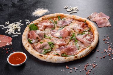 Koyu beton arka planda prosciutto ile taze, lezzetli İtalyan pizzası. İtalyan mutfağı