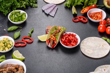 Biftek, domates, avokado, soğan ve salsa soslu Meksika tacoları.