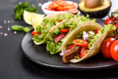 Biftek, domates, avokado, soğan ve salsa soslu Meksika tacoları.