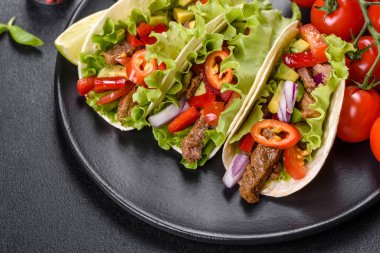 Biftek, domates, avokado, soğan ve salsa soslu Meksika tacoları.