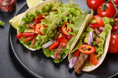 Biftek, domates, avokado, soğan ve salsa soslu Meksika tacoları.