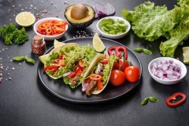 Biftek, domates, avokado, soğan ve salsa soslu Meksika tacoları.